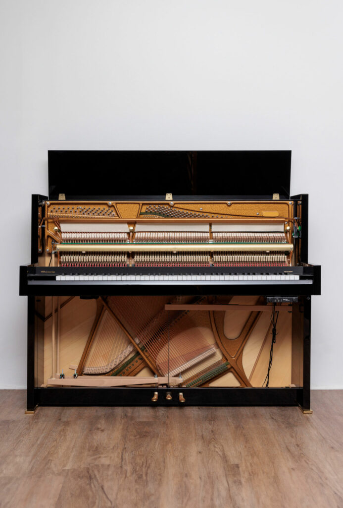 Piano droit noir ouvert, mécanisme interne visible