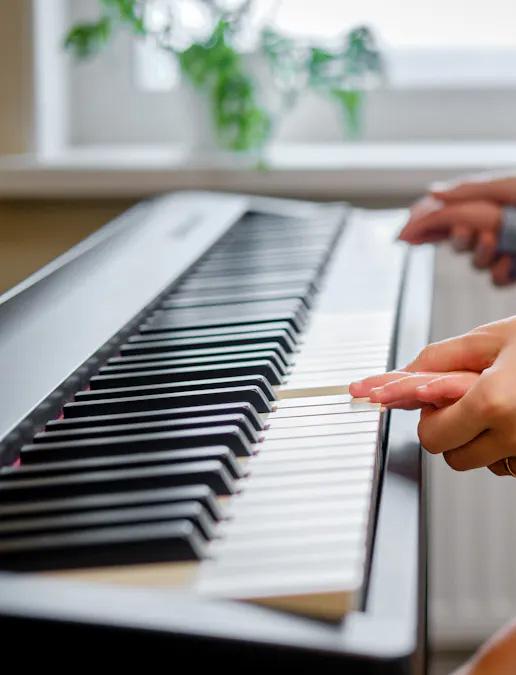 Mains de parent guidant des mains d'enfant sur un piano.